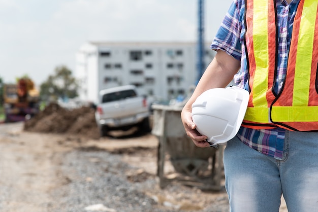 Travailleur ou architecte ingénieur en construction civile femme asiatique avec casque et gilet de sécurité heureux de travailler dans un bâtiment ou un chantier de construction