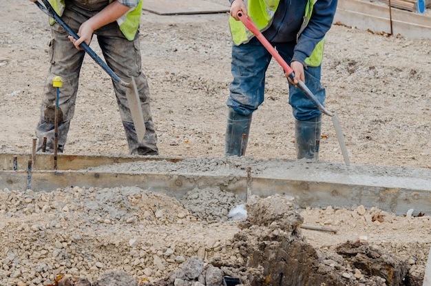 Travailleur au sol plaçant du béton humide à l'intérieur du coffrage pendant les travaux routiers et la construction de nouvelles routes