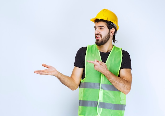 Travailleur en casque jaune montrant le côté gauche.