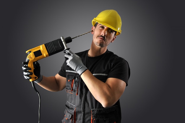 Travailleur avec casque jaune, perceuse et marteau