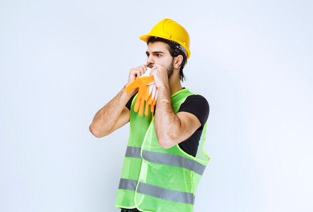 Travailleur en casque jaune sortant et démontrant ses gants d'atelier.