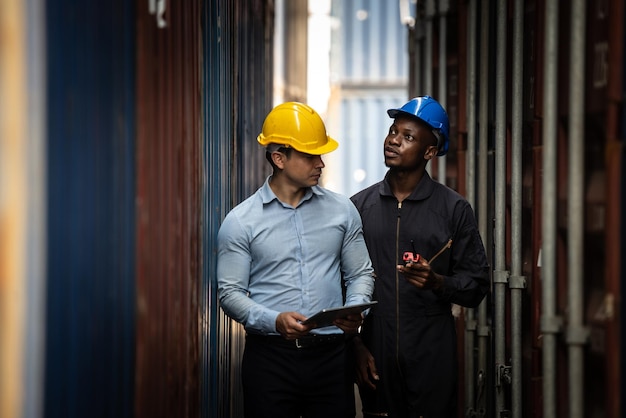 Photo un travailleur caucasien utilise un smartphone et une tablette pour les affaires travaillant au port pour les produits de transfert