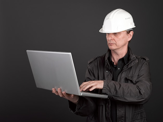 Travailleur en chemise noire et costume tenant un ordinateur portable