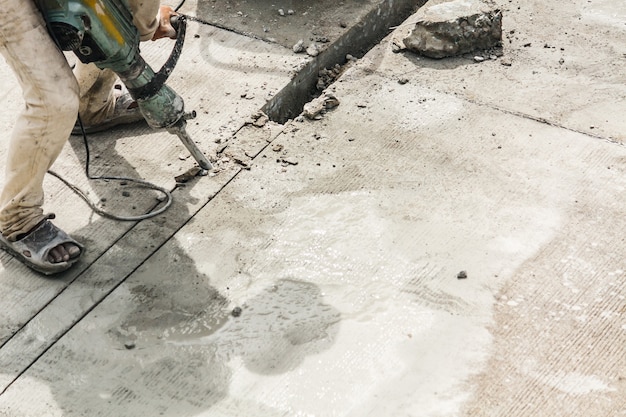 Travailleur de la construction à l'aide de marteau-piqueur de surface en béton