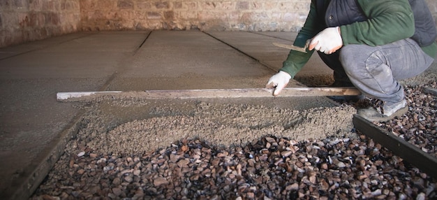 Le travailleur de la construction aligne le plancher de chape en béton