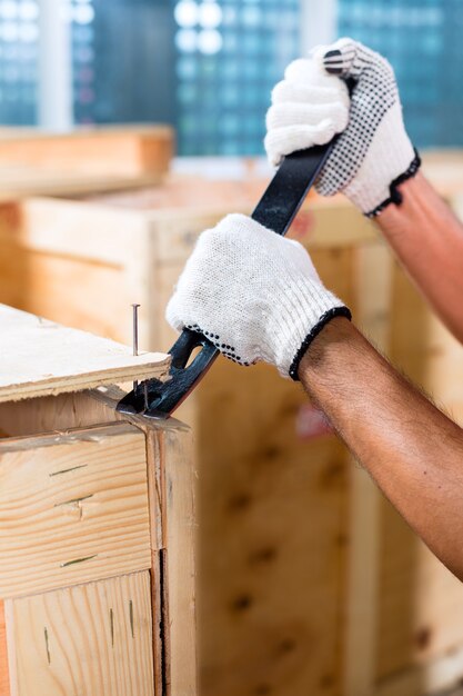 Travailleur de la construction sur un chantier de construction fermer une boîte en bois ou un conteneur de fret avec un marteau et un clou