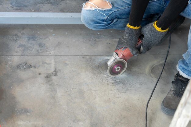 Le travailleur de la construction coupe le sol à l'aide d'une machine à lame moyenne pour maintenir la forme du cercle avec beaucoup de poussière autour pour installer un placard avec