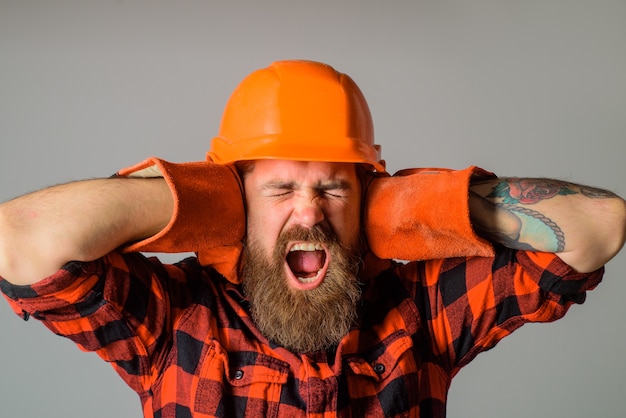 Travailleur de la construction en criant constructeur barbu dans un casque et des gants de travail en criant constructeur en dur