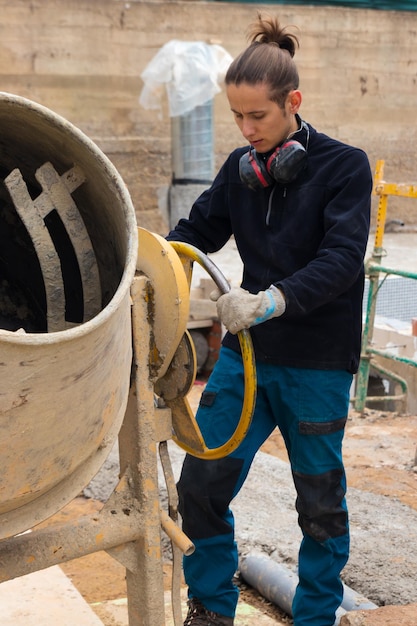 Travailleur de la construction faisant du béton dans la bétonnière sur le chantier