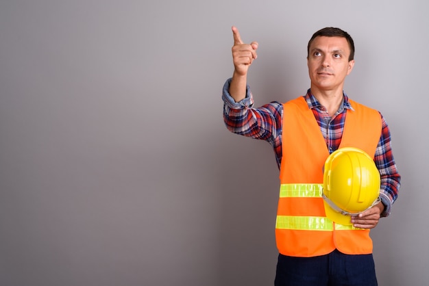 Travailleur de la construction de l'homme contre le mur gris