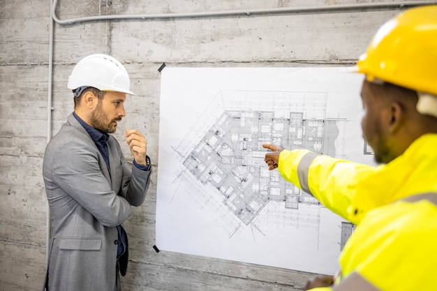 Travailleur de la construction et ingénieur en structure analysant le plan ou le plan du nouveau projet de construction