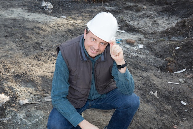 Travailleur de la construction masculin souriant dans un casque sur la construction du site