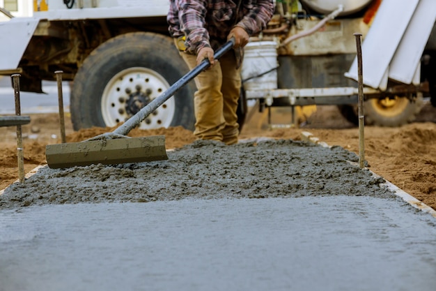 Travailleur de la construction pour ciment pour trottoir dans les travaux de béton avec camion malaxeur avec brouette