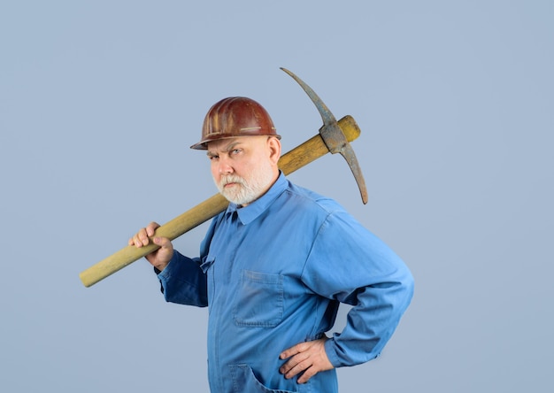 Travailleur de la construction sérieux avec pioche ouvrier avec pioche maçon mâle en casque avec