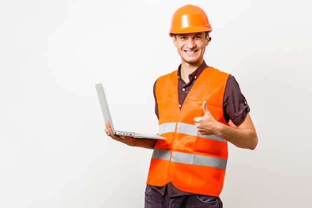 Travailleur de la construction sympathique tenant un ordinateur portable avec un espace noir pour votre message. Isolé sur blanc.