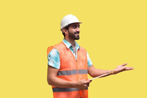 Travailleur de la construction tenant le presse-papiers et posant sur fond jaune modèle pakistanais indien