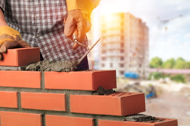 Le travailleur construit un mur de briques