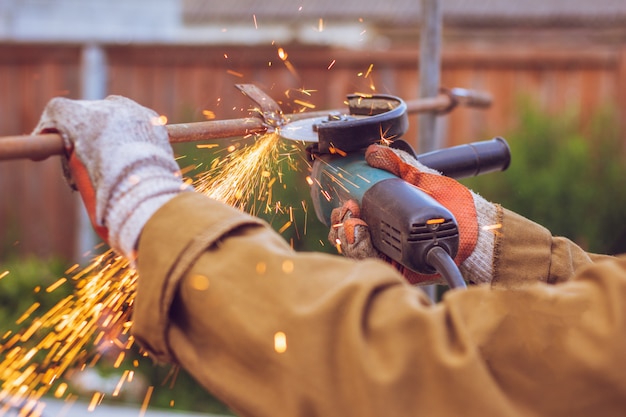 Le travailleur coupe le broyeur en métal. De belles étincelles volent sous le disque de coupe