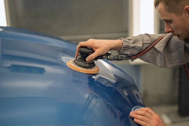 Travailleur Dans L'atelier De Peinture D'une Carrosserie De Voiture, Ponçage  Des Objets Peints