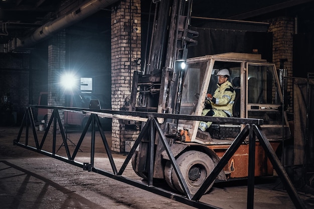 Le travailleur déplace la construction de métaux lourds à l'aide d'un camion spécial dans une usine de métal.