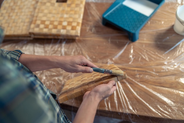 Travailleur du bois appliquant une couche de peinture sur la pièce de la boîte