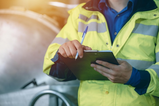 Travailleur du personnel de l'ingénieur en gros plan avec la liste des horaires de vérification écrire l'entretien de l'enregistrement remplacer la date de service