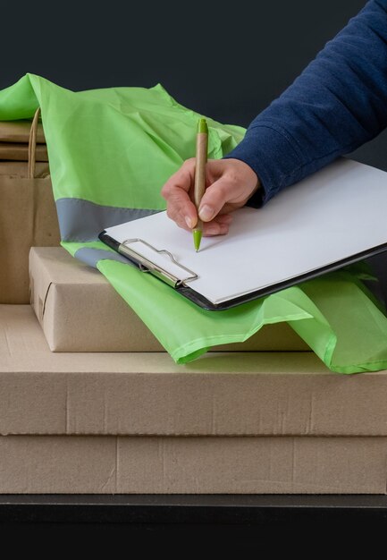 Photo le travailleur du service de livraison reste près du lieu de travail avec des boîtes et écrit sur tablette.