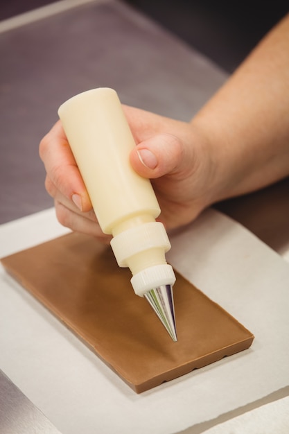 Travailleur écrit avec poche à douille sur plaque de chocolat