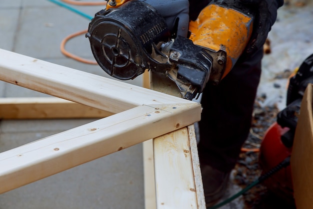 Le travailleur effectue les travaux de finition des murs avec une planche de bois blanche, en utilisant une ligne de niveau laser.