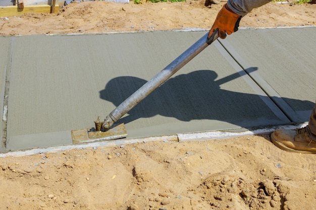 Travailleur enduisant le ciment de béton pendant le trottoir