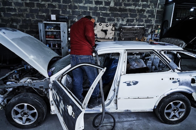 Photo le travailleur de l'entretien automobile répare la voiture