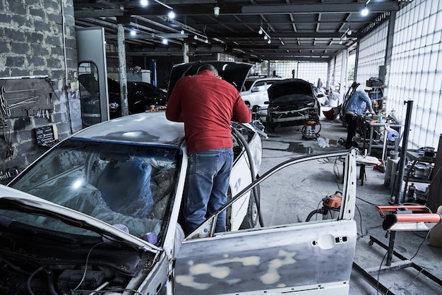 Photo le travailleur de l'entretien automobile répare la voiture