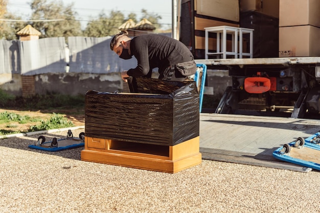 Travailleur enveloppant un meuble en bois avec une pellicule plastique