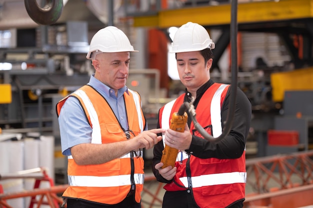 Travailleur de l'équipe d'ingénieurs enseignant aider à parler de la machine de production L'industrie et le travail dans le personnel de l'usine contrôlent la machine lourde dans l'usine