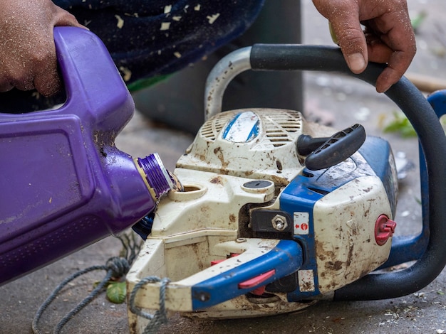 Le travailleur fait le plein de carburant à la tronçonneuse après le travail