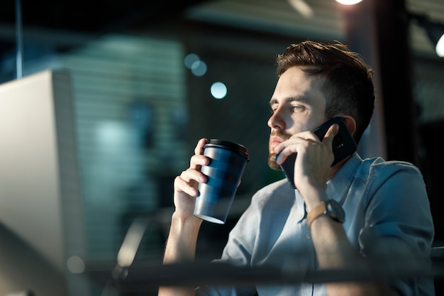 Travailleur fatigué avec du café tard dans le bureau