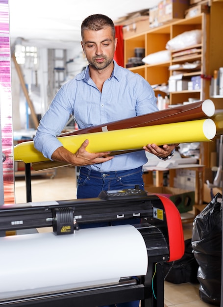 Travailleur de l'imprimerie mâle avec des rouleaux de papier de couleur