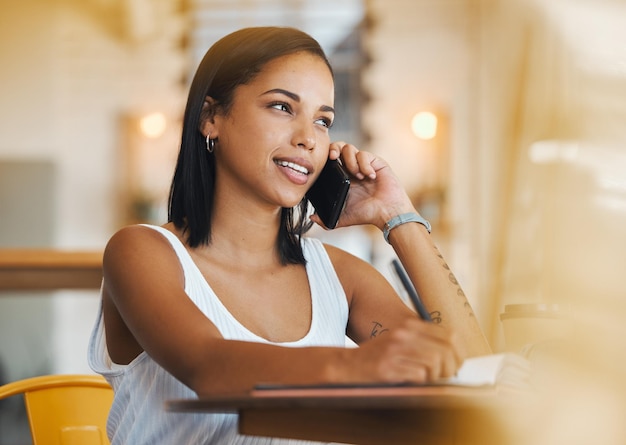 Travailleur indépendant travaillant dans un café parlant au téléphone d'une stratégie de croissance Jeune étudiante avec un état d'esprit positif travaillant à distance dans un café et ayant une conversation mobile