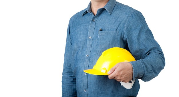 Le travailleur ingénieur porte une chemise bleue et tient un casque de sécurité jaune sur un fond isolant.