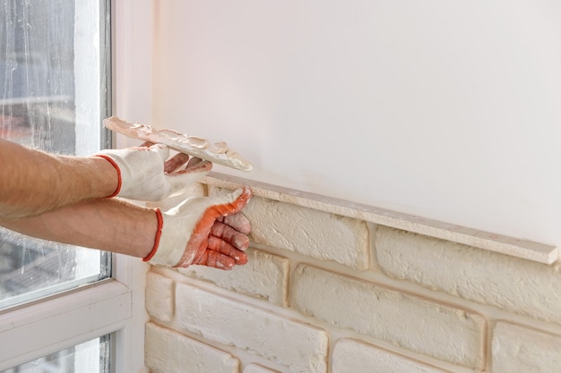 Un travailleur installe des carreaux de brique de gypse sur le mur.