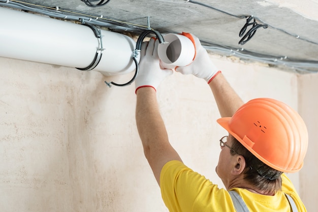 Le travailleur installe un système de ventilation dans l'appartement.