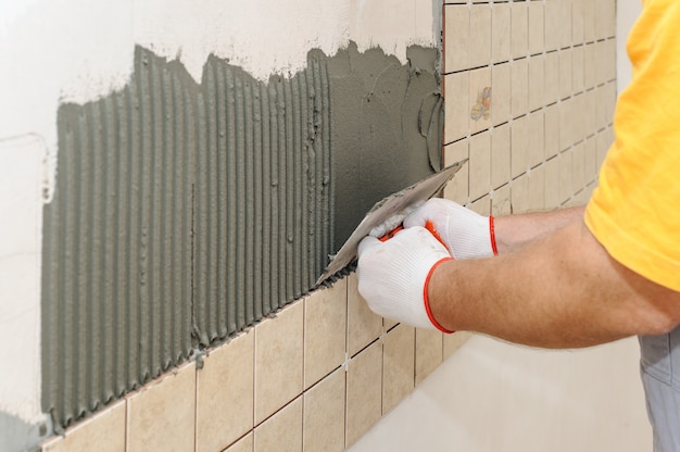 Travailleur instillant des carreaux sur le mur de la cuisine.