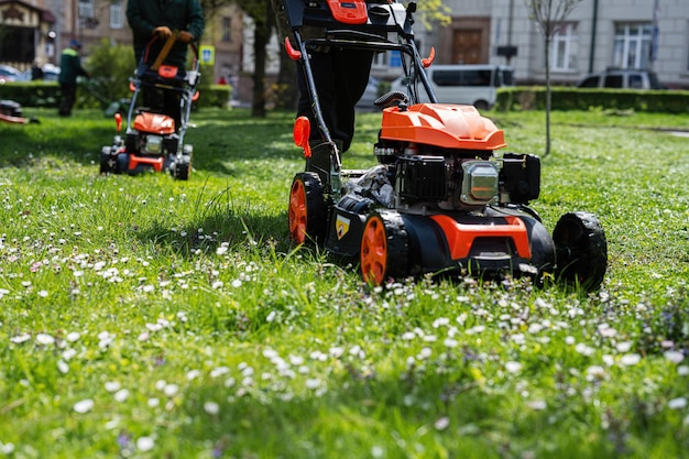 Travailleur jardinier des services communaux homme utilisant une tondeuse à gazon pour couper l'herbe dans le parc de la ville