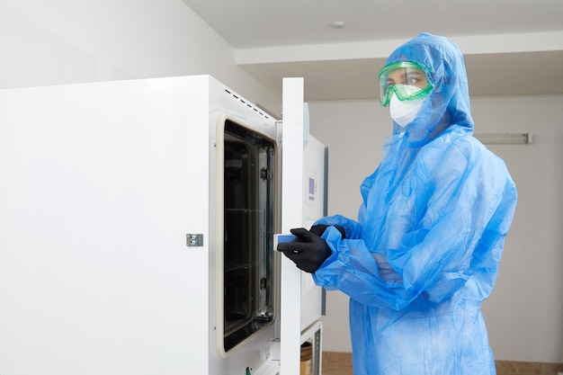 Travailleur de laboratoire opérant un stérilisateur autoclave de laboratoire moderne