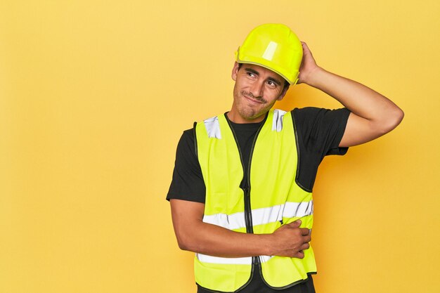 Photo travailleur latino en gilet jaune et casque touchant l'arrière de la tête en pensant et en faisant un choix