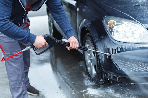 Un travailleur de lavage de voiture professionnel lave la voiture du client