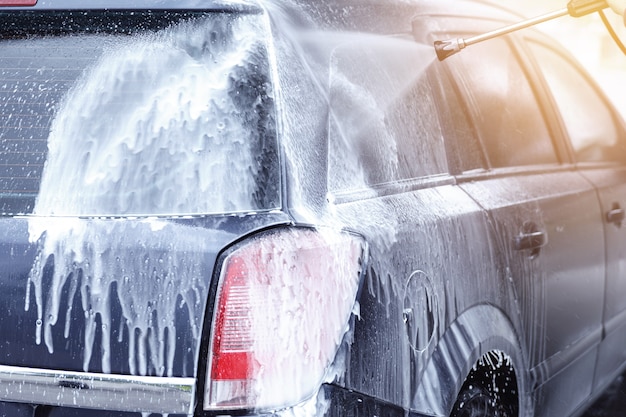 Un travailleur de lavage de voiture professionnel lave la voiture du client