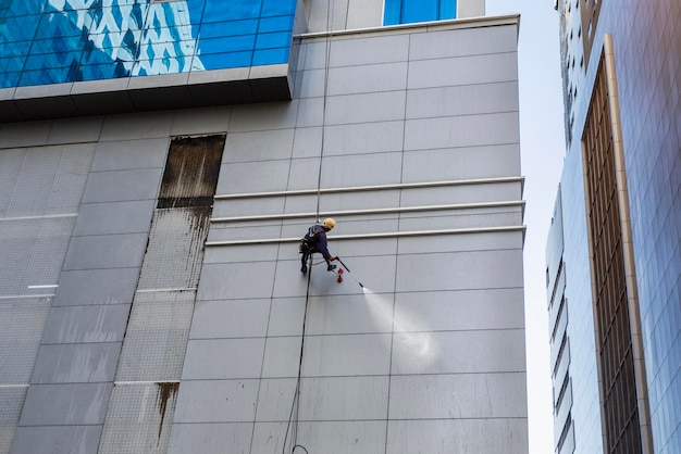 Un travailleur lave la façade du mur en hauteur sur un bâtiment moderne
