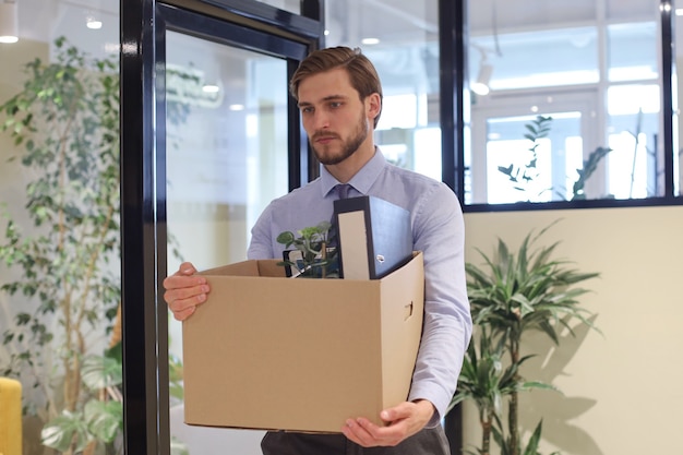 Travailleur licencié quittant le bureau avec ses fournitures de bureau.