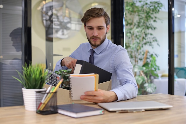 Un travailleur licencié triste prend ses fournitures de bureau avec lui du bureau.